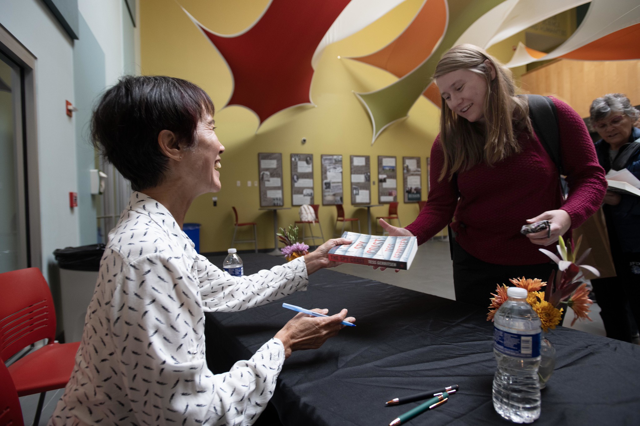 A woman signs copies of books.