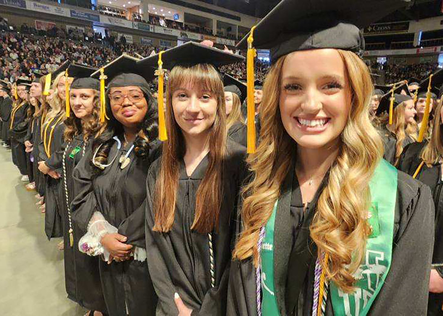 Smiling young people in caps and grows look at the camera.