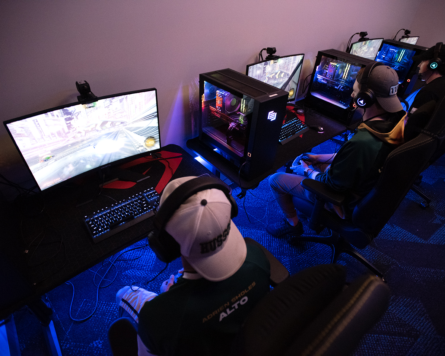 Three people play video games on screens.