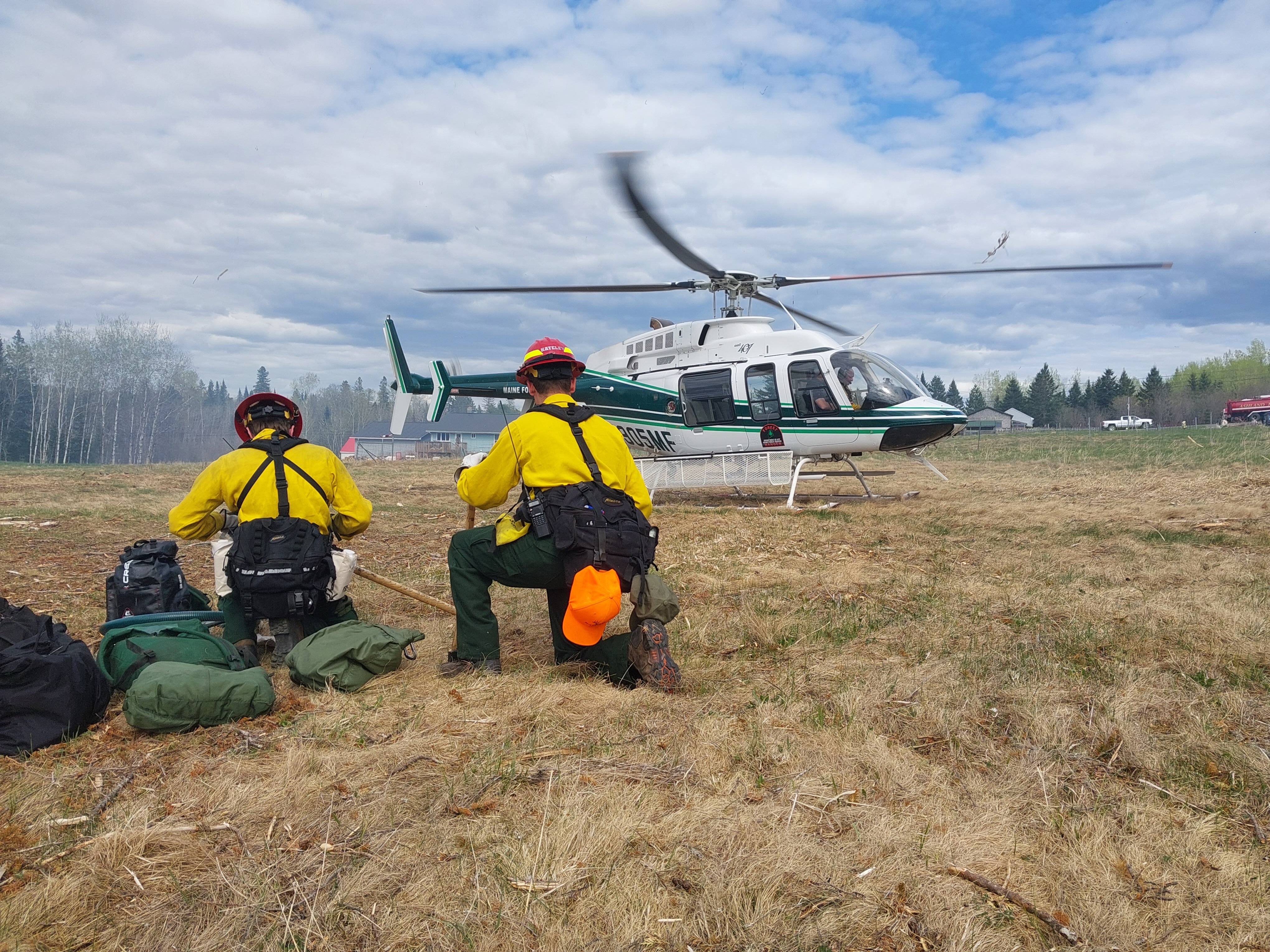 Two people are shown crouched facing a helicopter.