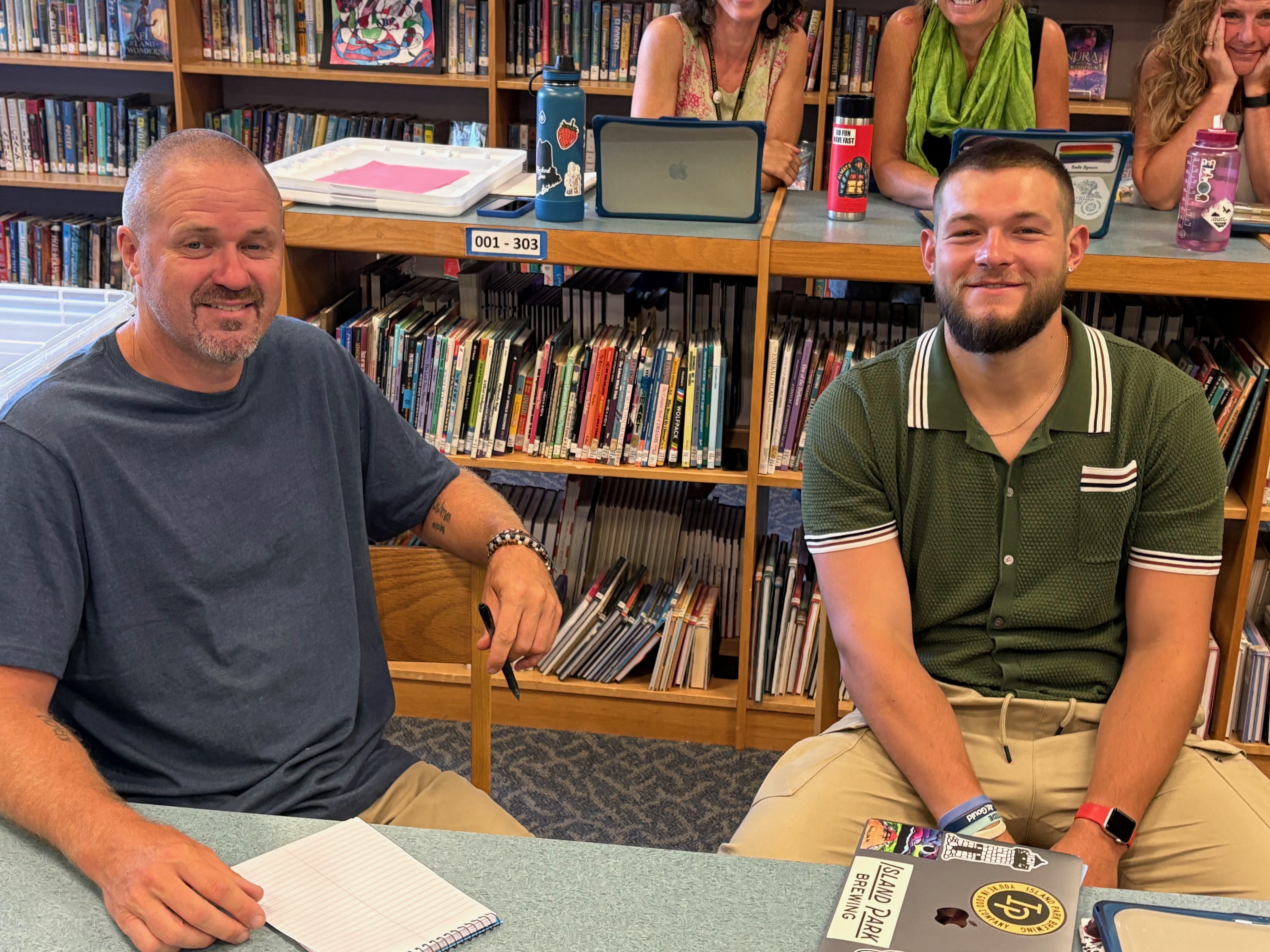 Two men sit together in a classroom