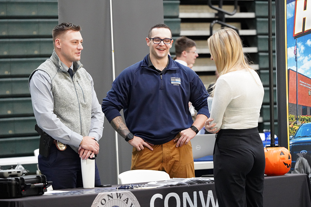 Two students speak to members of law enforcement at a career fair.