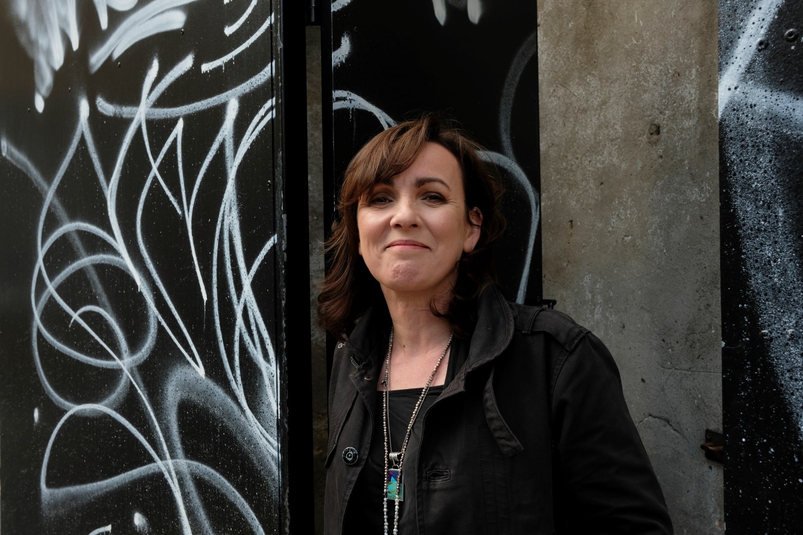 Karan Casey standing in front of a wall with graffiti on it.