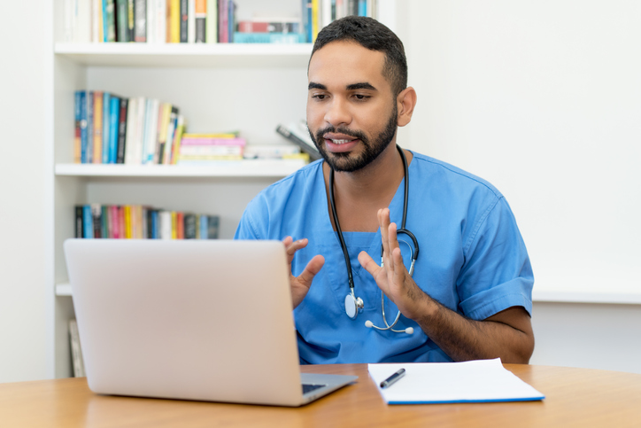 Male nurse talking to a patient virtually on a tablet.