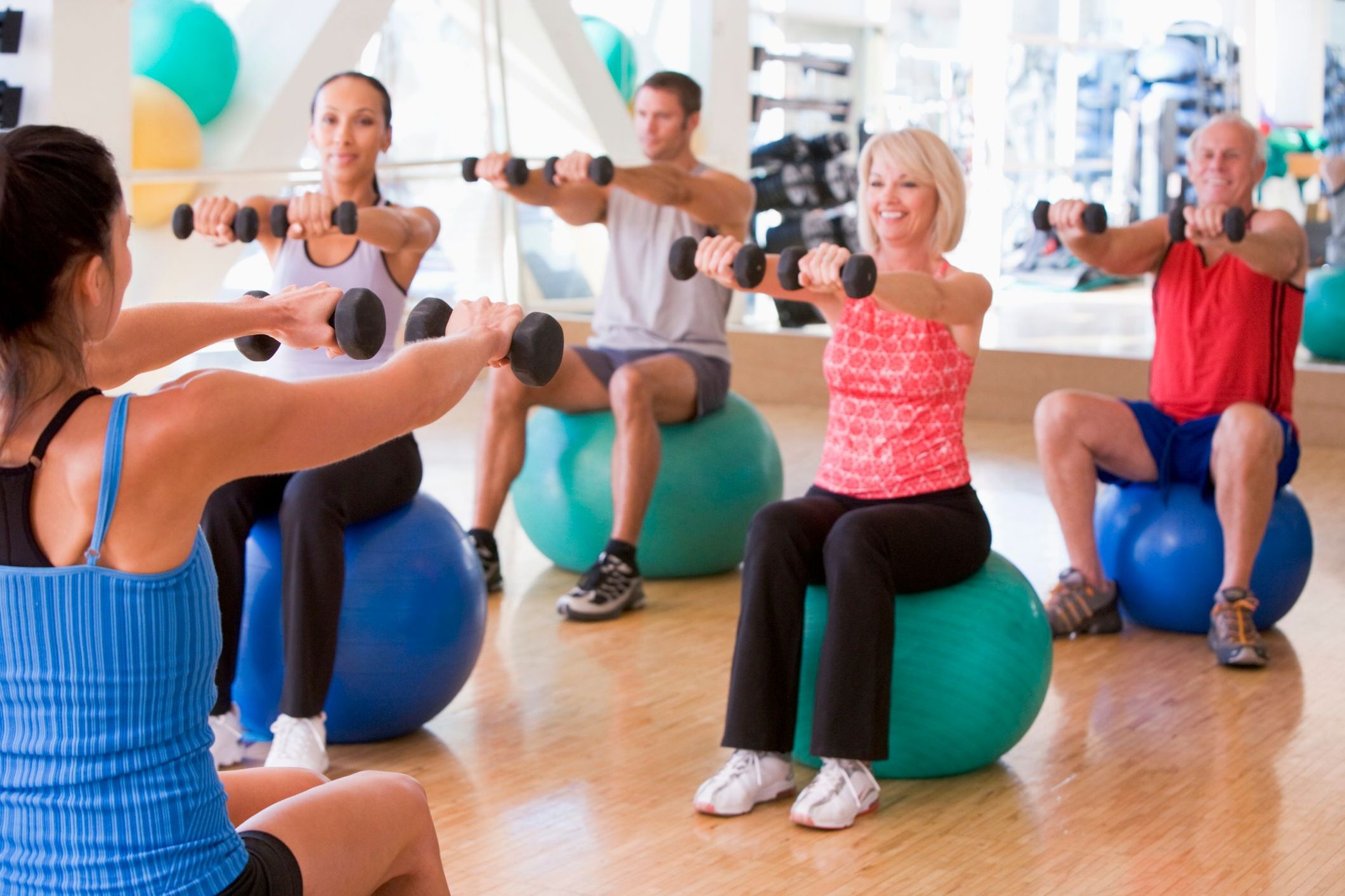 Fitness instructor leading a class in which people are using exercise balls.