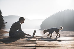 man working on lake dog with dog