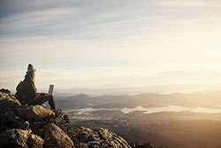 student working on top mountain with laptop