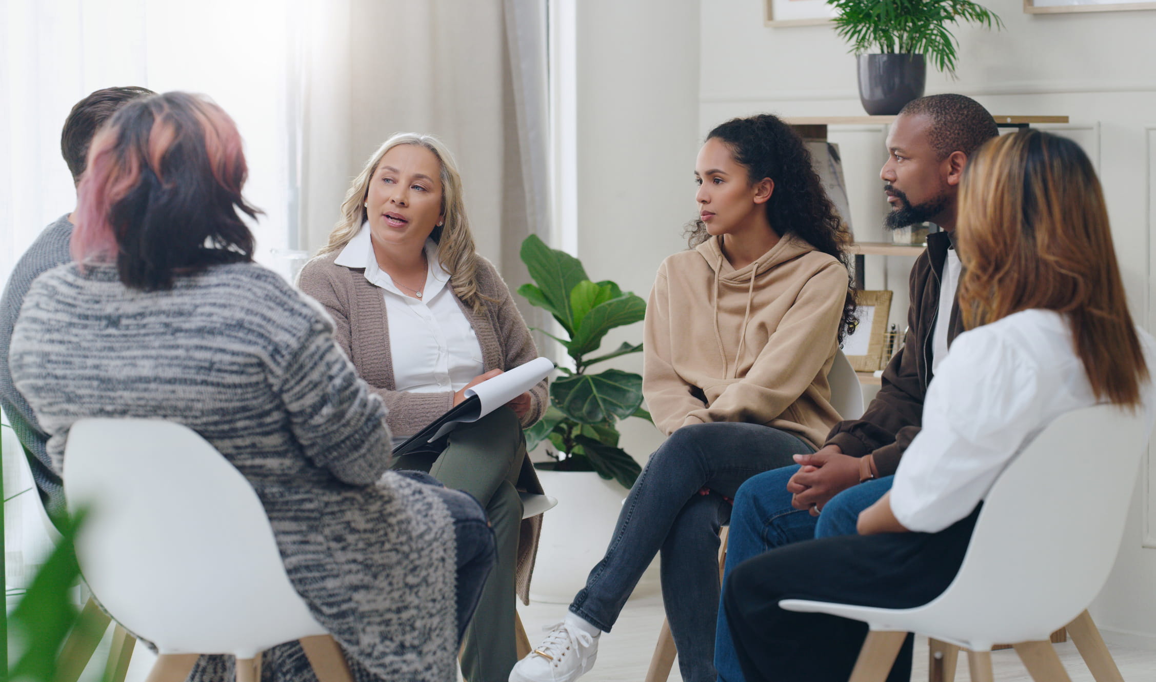 A group counseling session involving six people sitting in a circle.