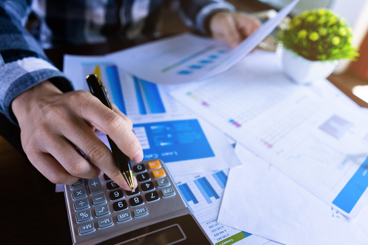 person using calculator while looking at business documents