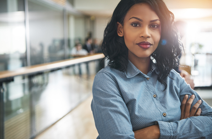 woman standing confidently with arms crossed in an office