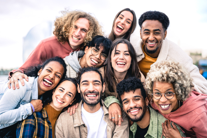 a group of people of different genders and ethnicities taking a selfie