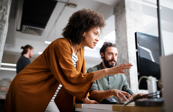 woman pointing to something on a computer screen in front of a man