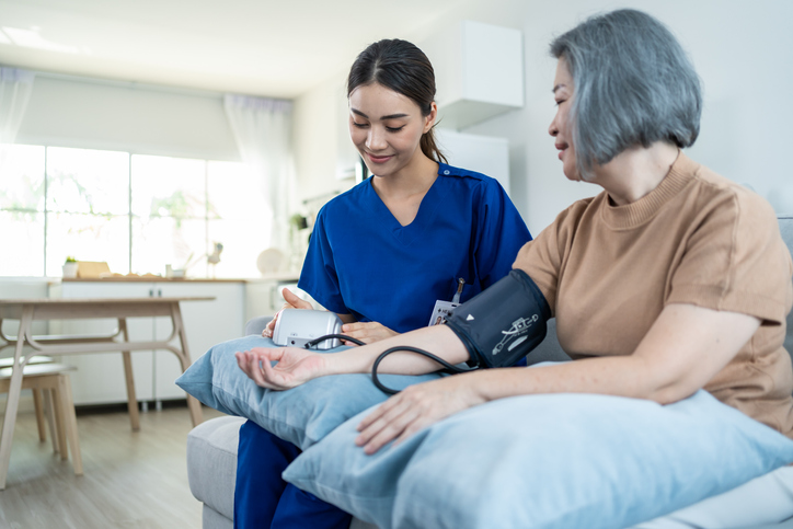 Nurse takes patient's blood pressure inside the patient's home