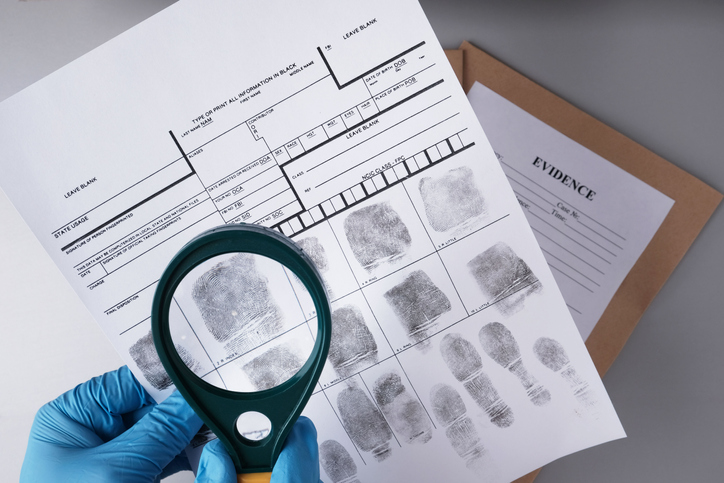 Person looking at finger prints through a magnifying glass.