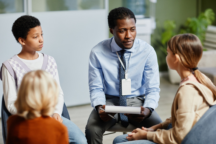 Male therapist leading a group therapy session.