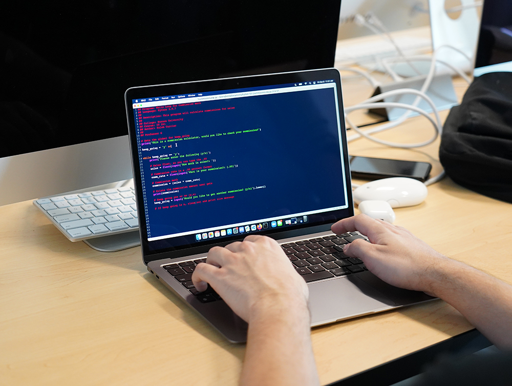 Person typing code on a laptop computer.