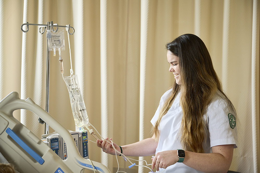 Nursing student checking a patient's IV fluid.