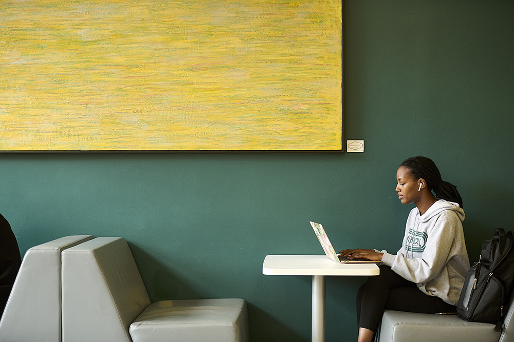 Girl working on a laptop computer while where headphones.