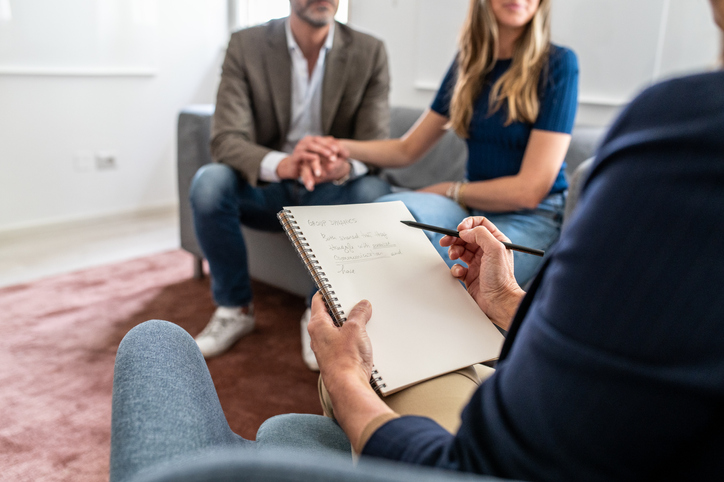 Therapist taking notes during a couple's counseling session.