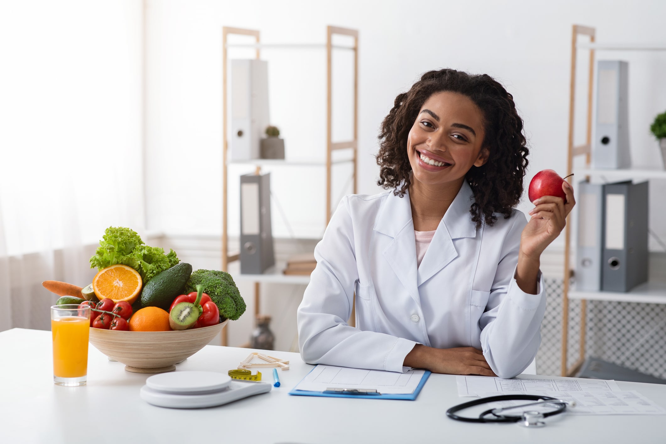 Nutrition professional sitting at a table and holding an apple.