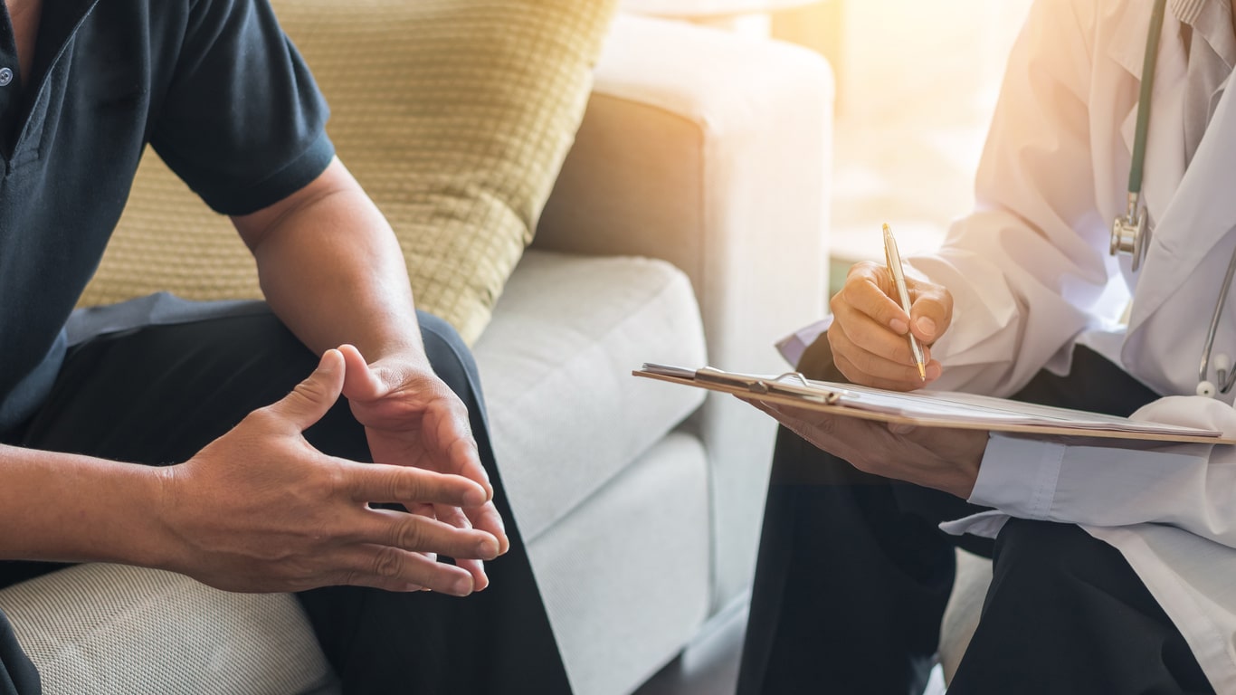 Doctor taking notes while speaking with patient.