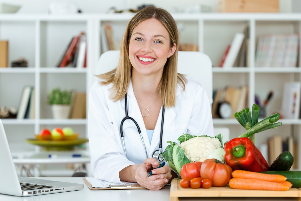 Smiling doctor sitting at a desk with fruit on it.