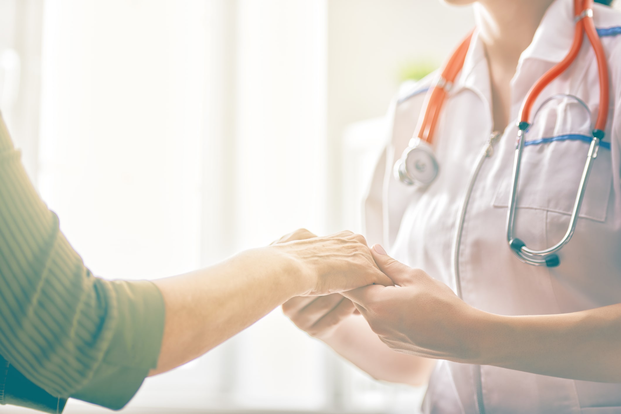 Close up of nurse holding a patient's hand.