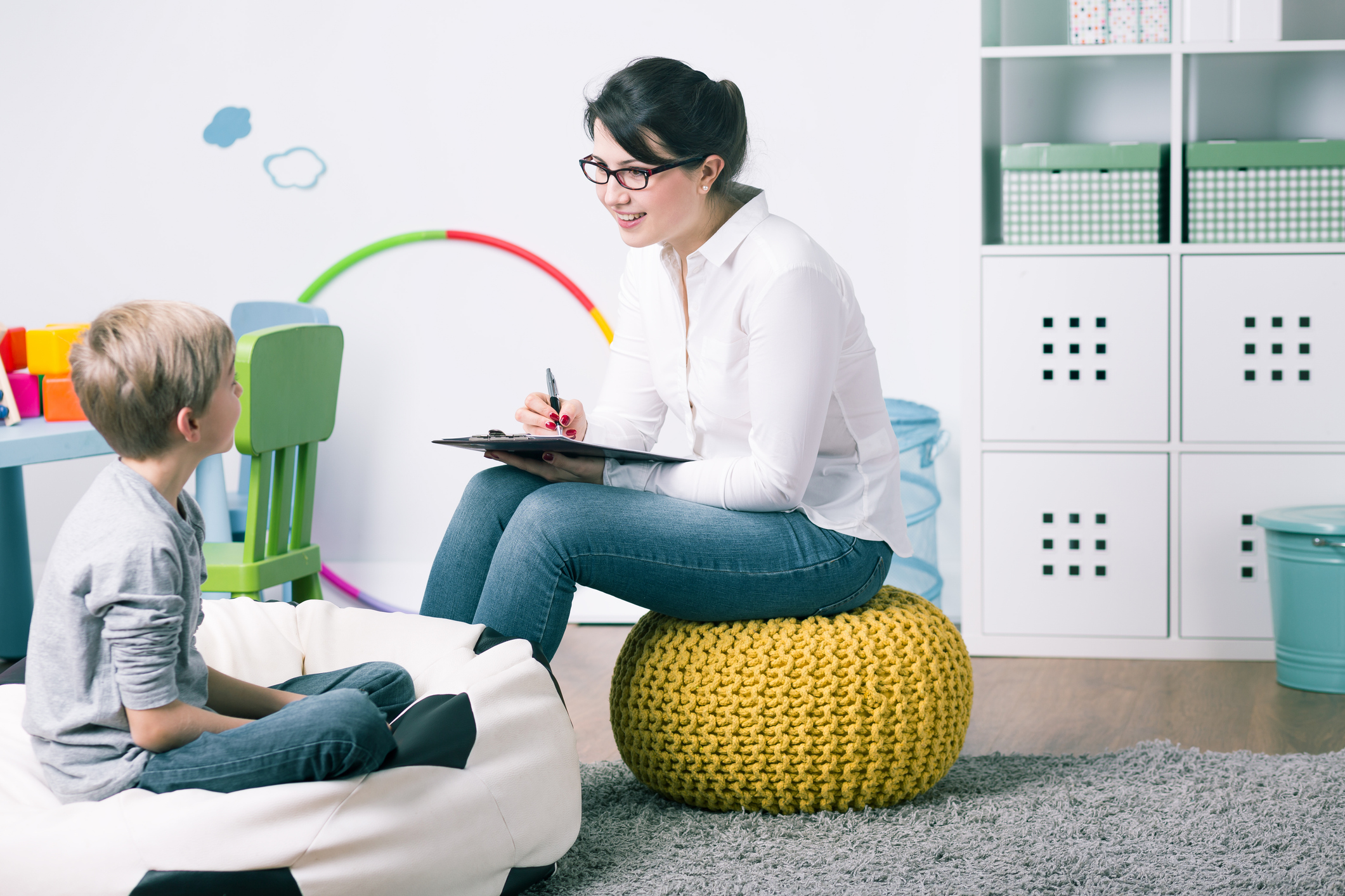 A female child psychologist speaking to a young boy.