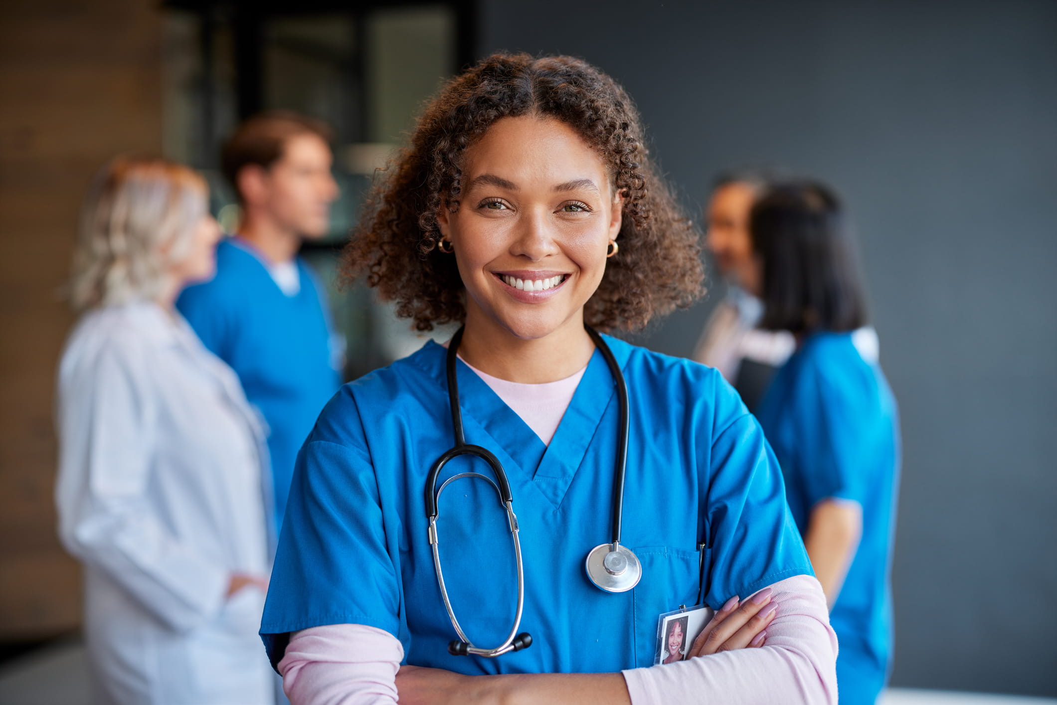A portrait of a smiling nurse with her arms folded.