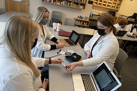 Students work in a classroom setting with faculty