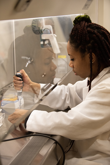 A student works in a lab transfering chemicals