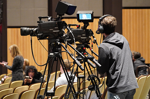 A New England School of Communications student works behind a camera at a live event