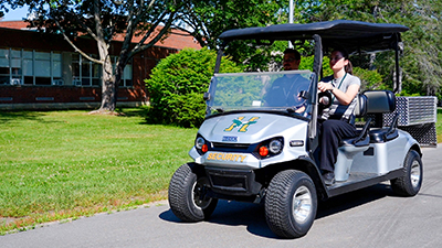 safety and security staff ride on a cart on the campus of Husson University