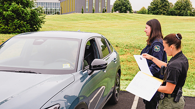 safety and security employees speak with a driver in a parking lot