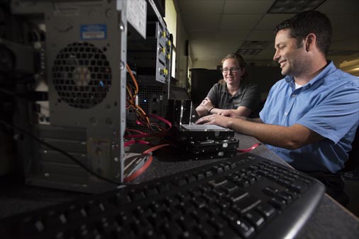 Employees work at a work bench in the Information Technology office